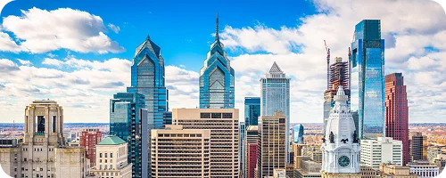 A vibrant view of the Philadelphia skyline featuring iconic glass towers under a clear sky.